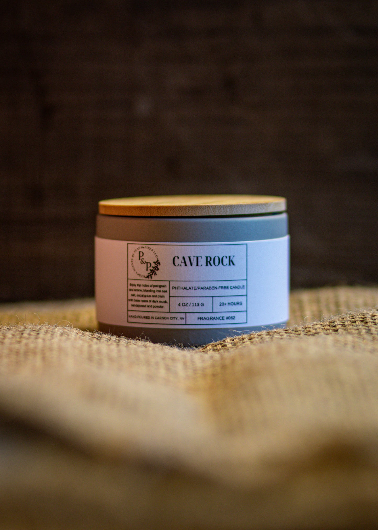 Cave Rock 4 oz ceramic candle by Peaks and Pines, grey ceramic jar with wood lid and white label on burlap.