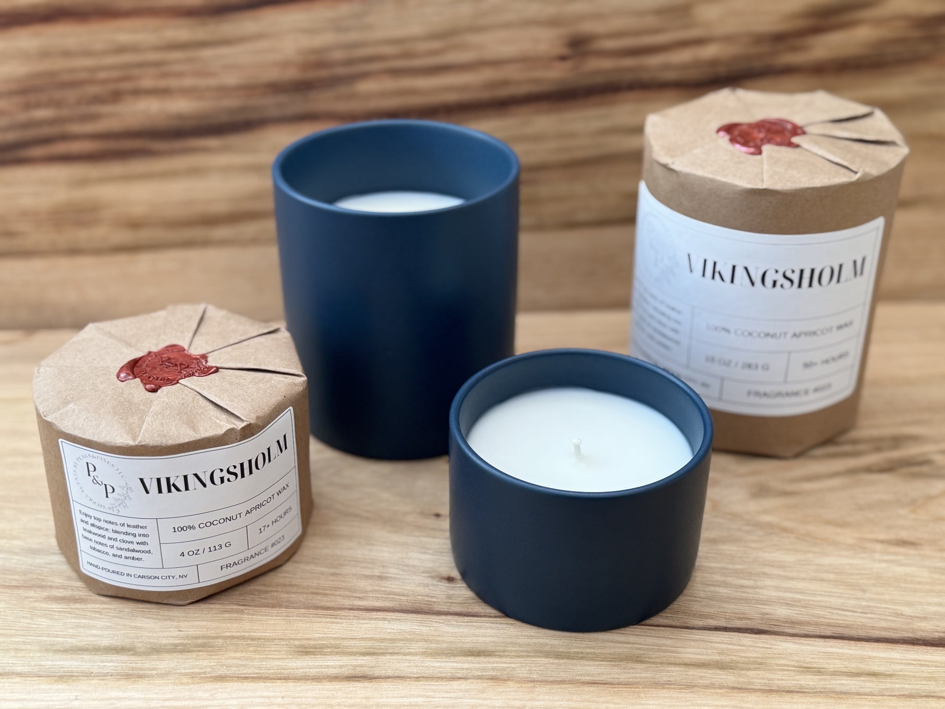 Vikingsholm 10 oz and 4 oz ceramic candles displayed together, wrapped and unwrapped and displayed on wood. 