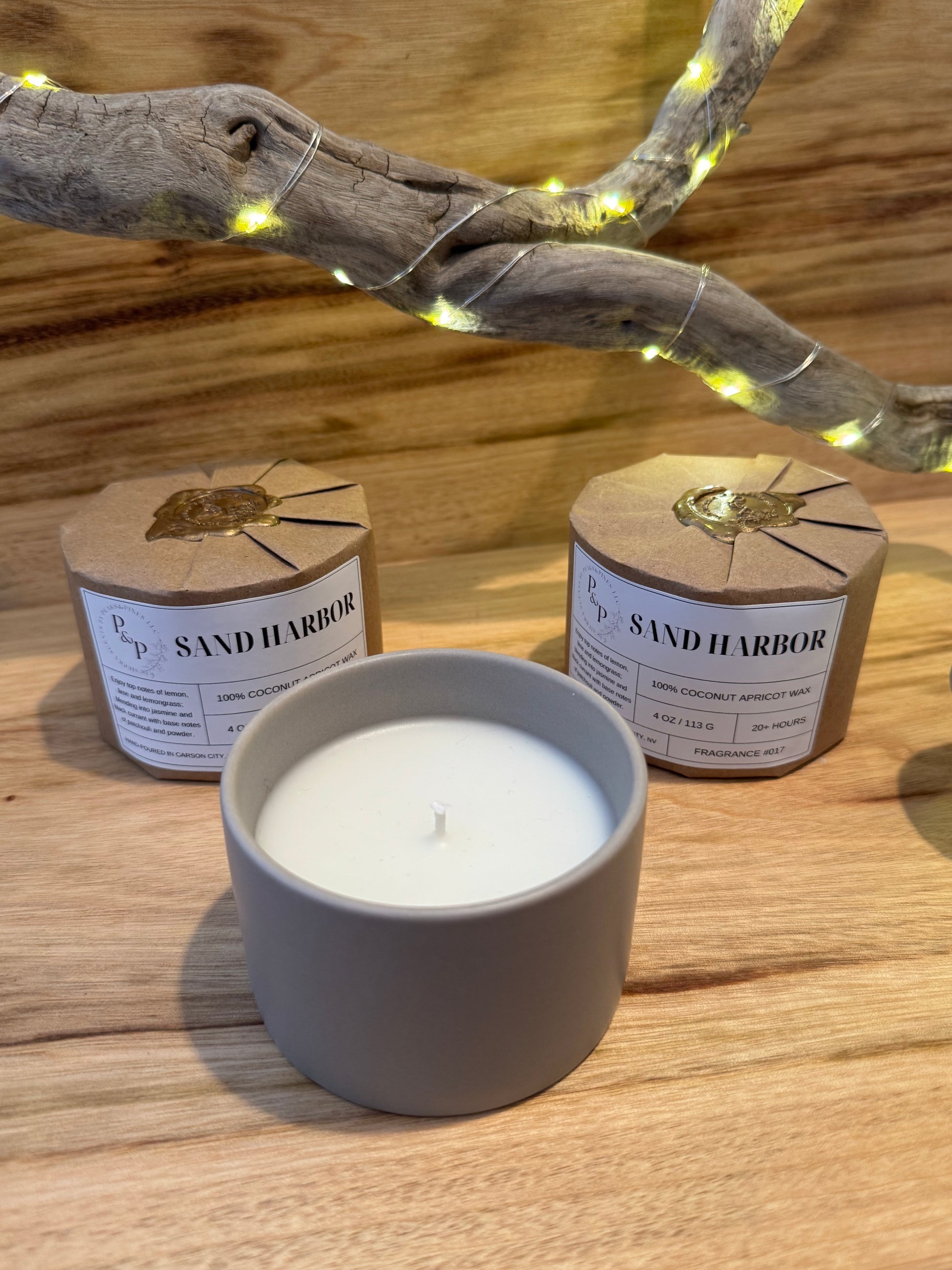 Three Sand Harbor 4 oz candles on a wooden surface, two wrapped with kraft paper and wax seal