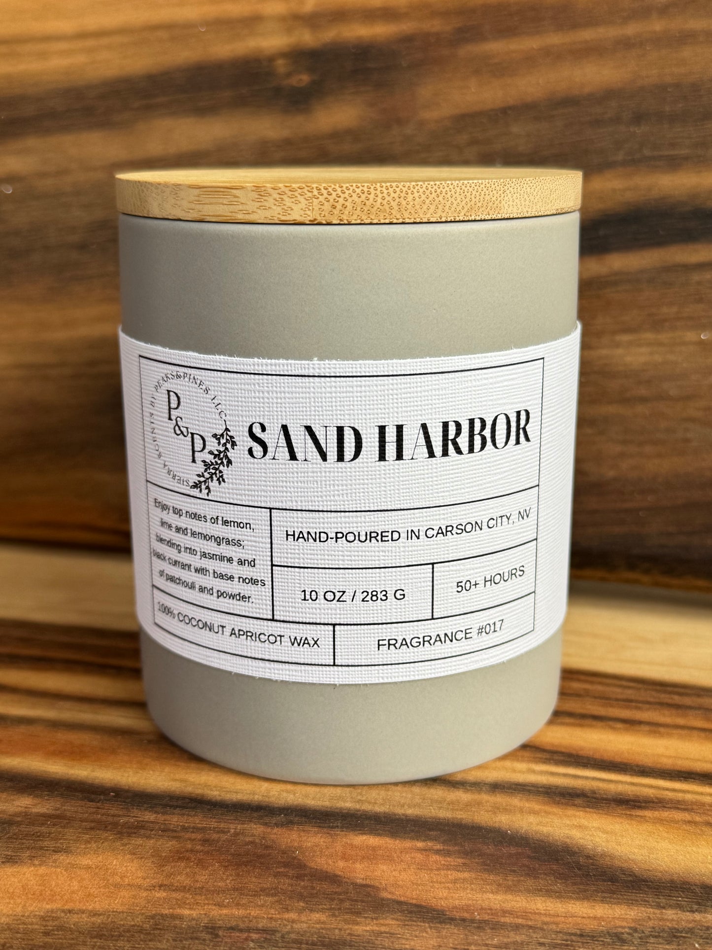 Sand Harbor 10 oz ceramic candle by Peaks and Pines, gray jar with wood lid and white label