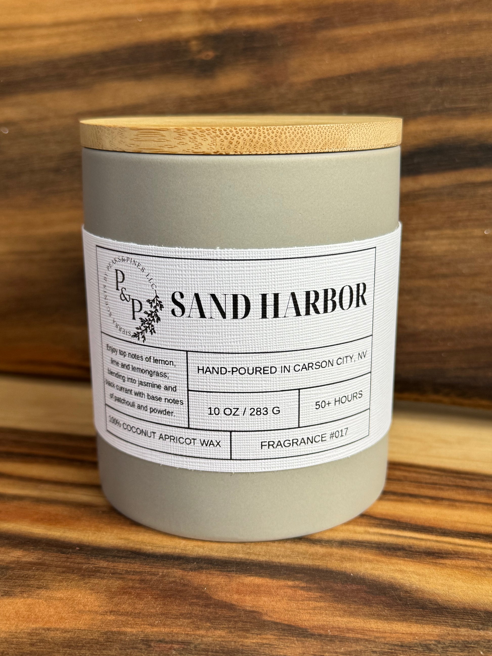 Sand Harbor 10 oz ceramic candle by Peaks and Pines, gray jar with wood lid and white label