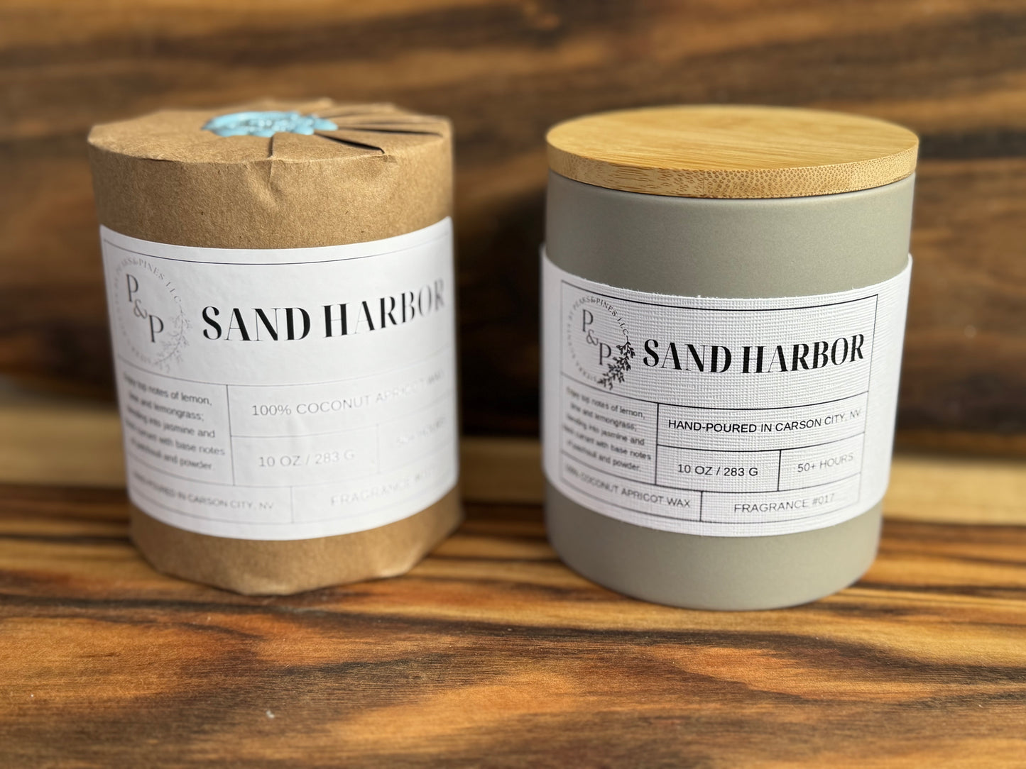 Two candles Sand Harbor scented candles on a wooden surface with a wooden background. One wrapped with Kraft paper and wax seal and the other with white label. 