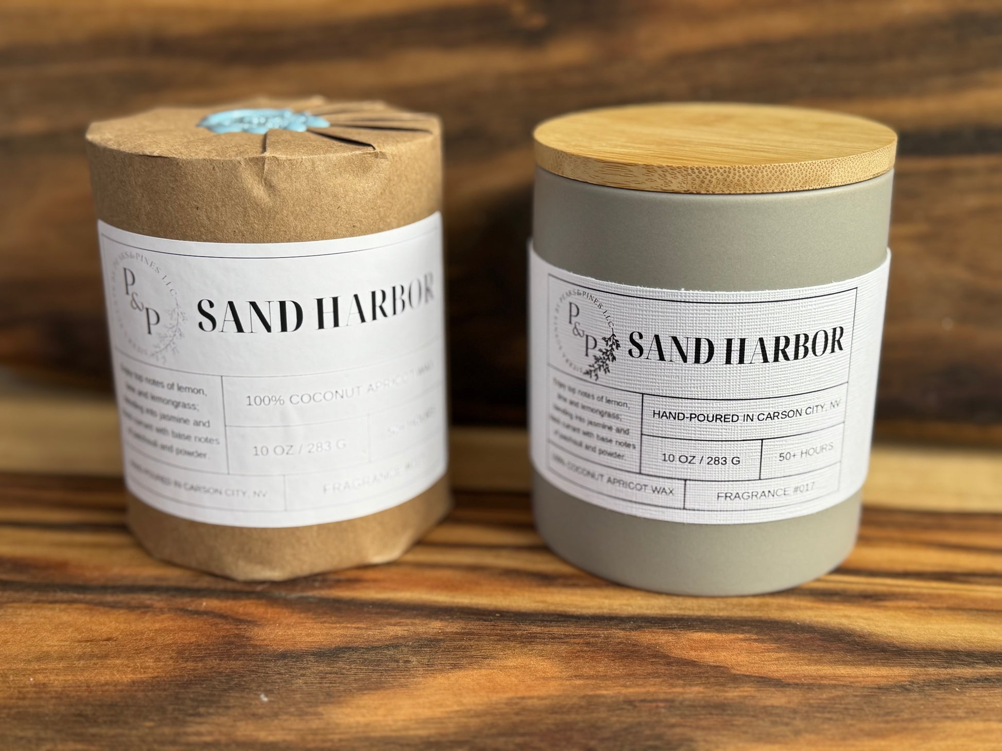 Two candles Sand Harbor scented candles on a wooden surface with a wooden background. One wrapped with Kraft paper and wax seal and the other with white label. 