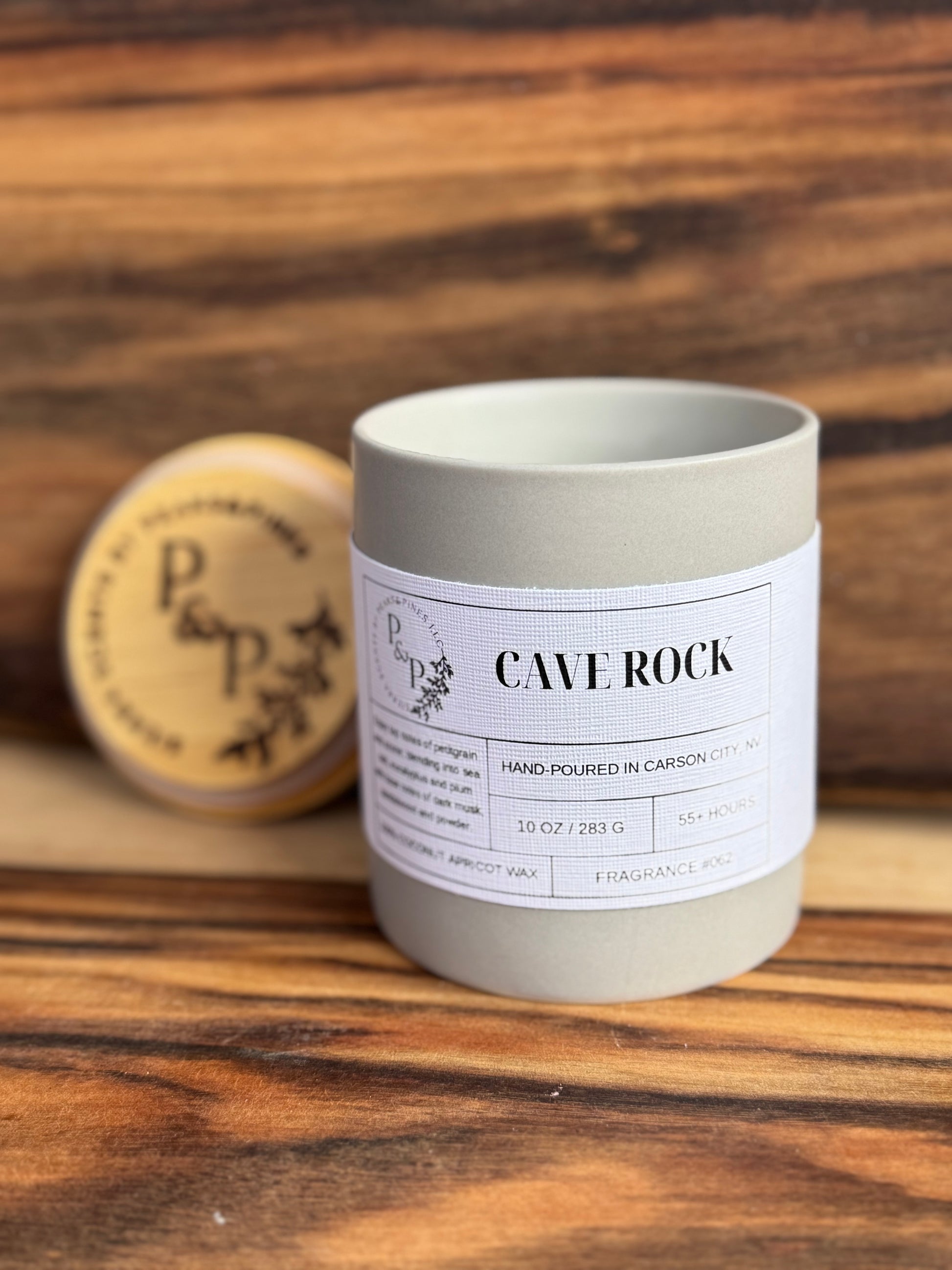 Cave Rock 10 oz candle close-up showing grey ceramic jar and branded wood lid
