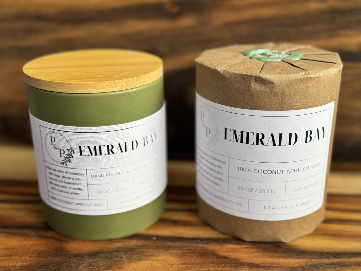 Two Emerald Bay 10 oz candles on a wooden surface, one wrapped in kraft paper with wax seal.