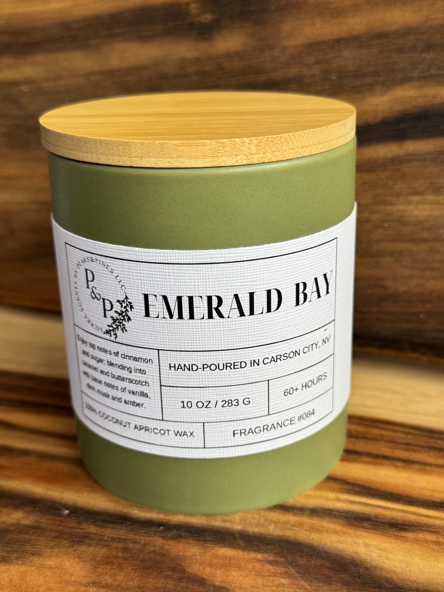 Emerald Bay 10 oz ceramic candle by Peaks and Pines, green ceramic jar with wood lid and white label.
