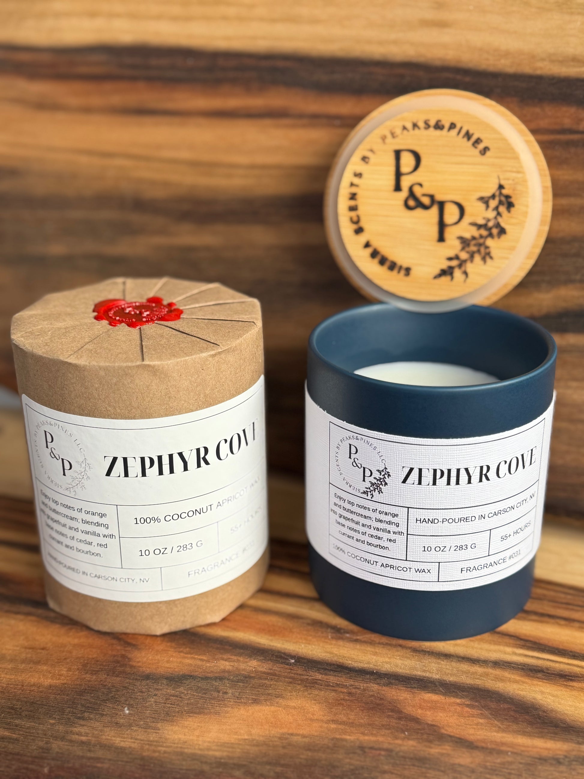 Two Zephyr Cove 10 oz ceramic candles by Peaks and Pines. One wrapped in Kraft paper with wax seal and one unwrapped showing blue label and white label with wood branded lid.