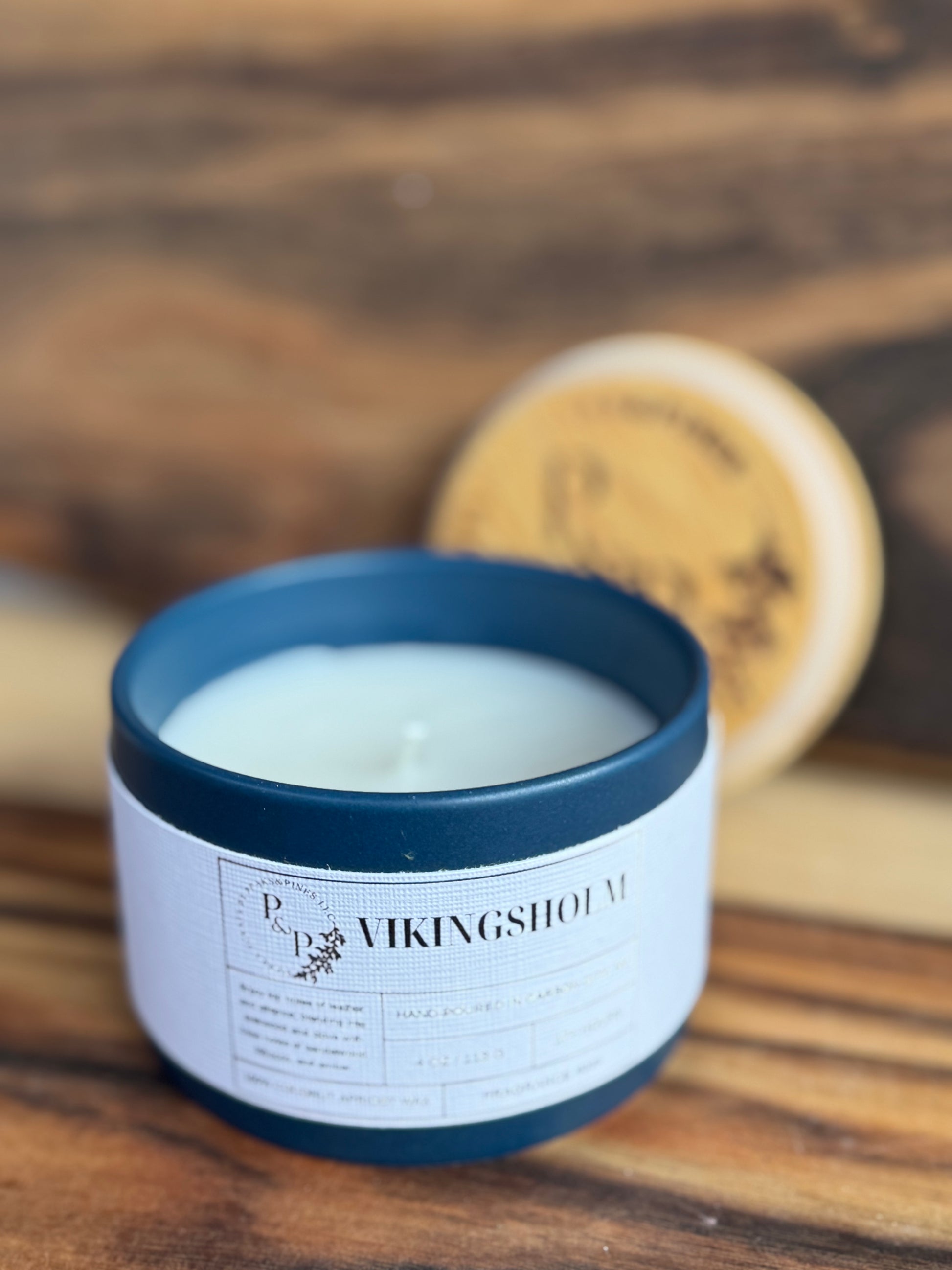 Vikingsholm 4 oz ceramic candle by Peaks and Pines, blue ceramic jar with branded wood lid and white label.