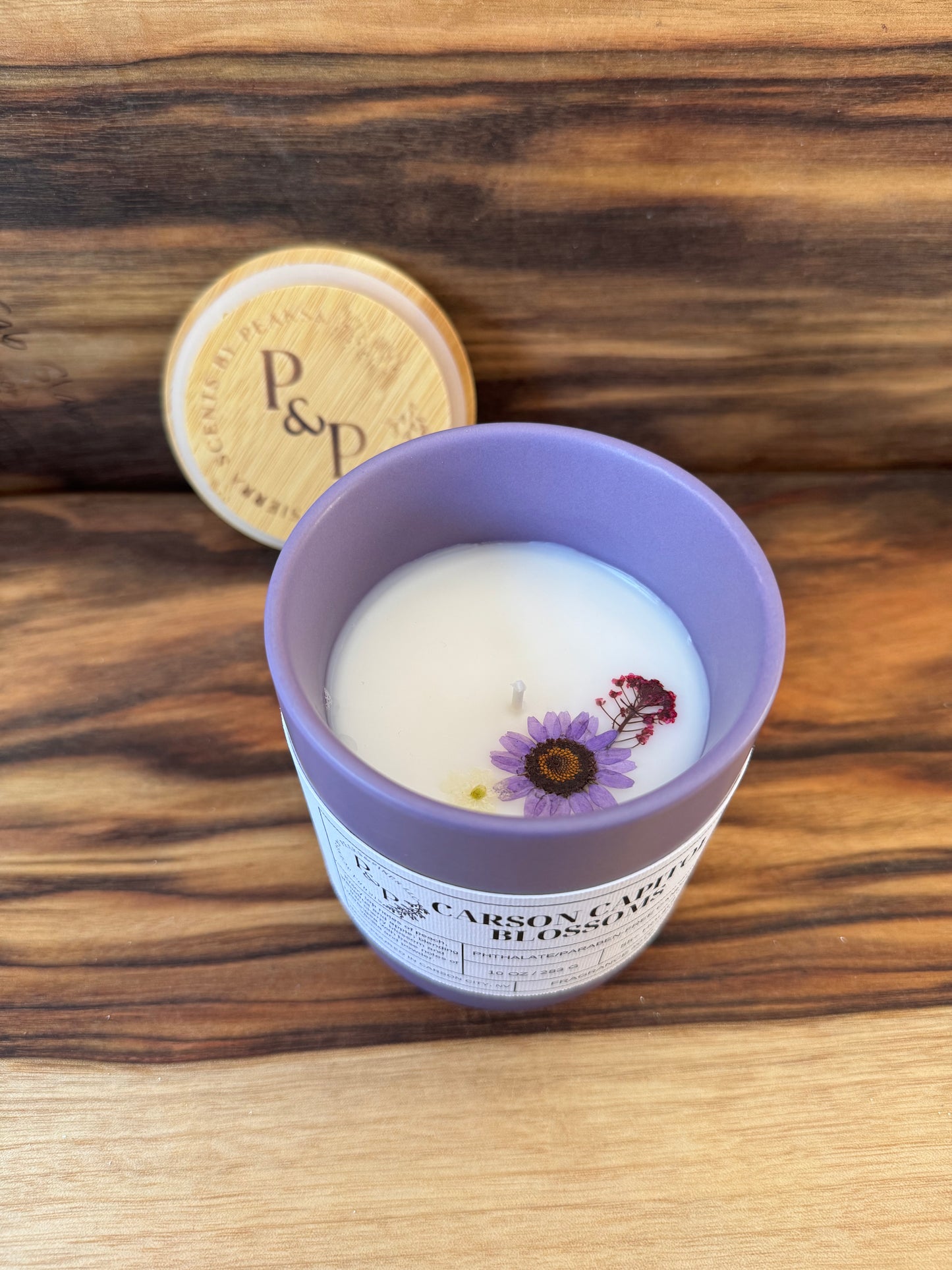 Carson Capitol Blossoms 10 oz purple ceramic candle by Peaks and Pines, botanical impressions line with pressed flowers in the wax and branded wood lid
