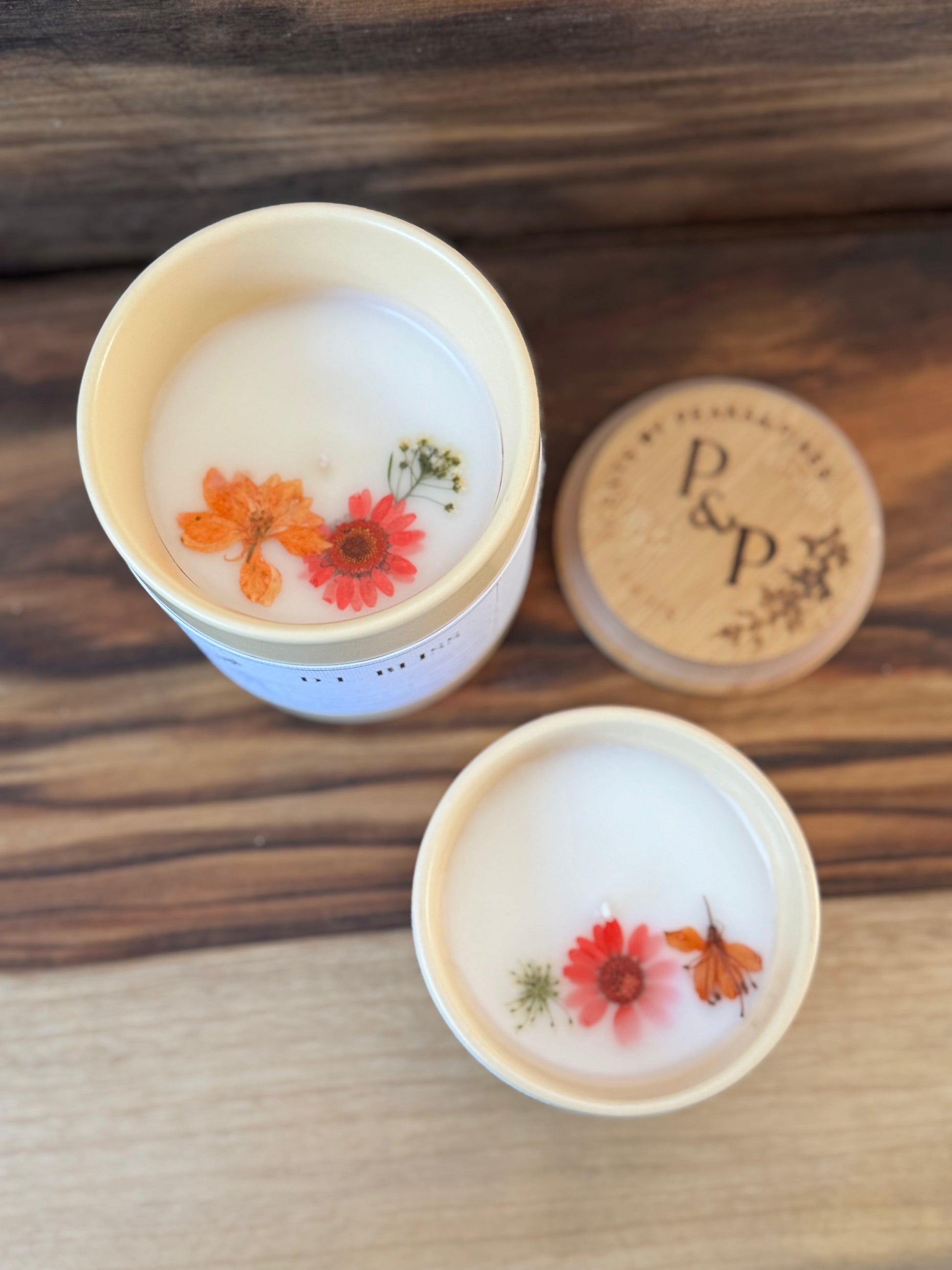 D.L. Bliss 4 oz and 10 oz ceramic candles from the Peaks and Pines botanical impressions line displayed together showing pressed flowers embedded in the wax surface