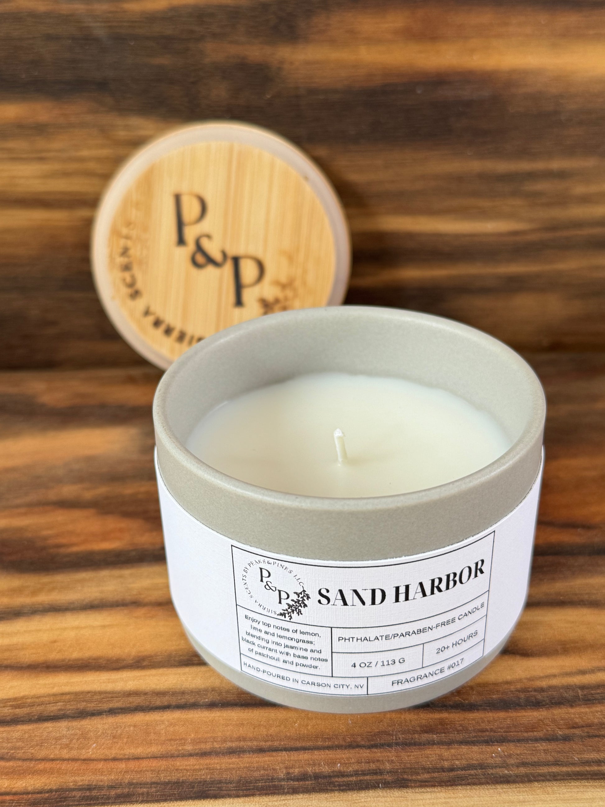 Sand Harbor 4 oz candle unwrapped showing gray ceramic jar and branded wood lid