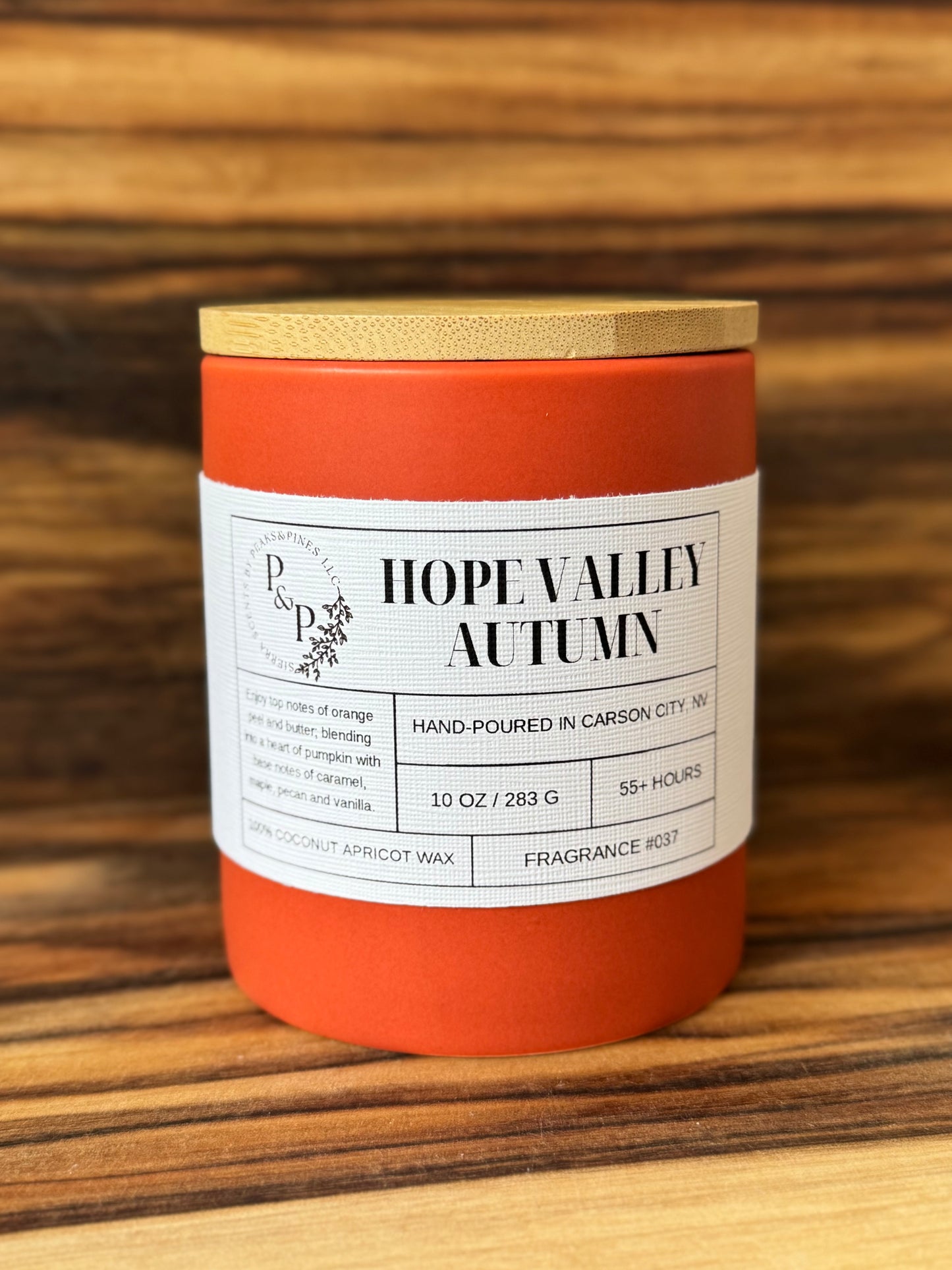 Hope Valley Autumn 10 oz ceramic candle by Peaks and Pines, orange ceramic jar with wood lid and white label